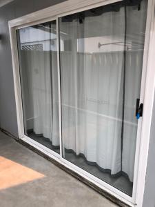 uma janela de vidro com cortinas brancas num quarto em Agapi on Cambridge em Umina