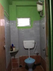 een groene badkamer met een toilet en een raam bij Pushpa Di Ghar in Calcutta