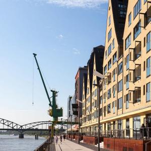 a building next to a river with a bridge at Großzügiges Zimmer mit Badezimmer in Rheinwohnung in Cologne