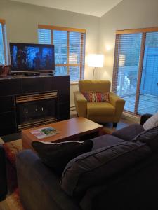 a living room with a couch and a tv and a fireplace at Tyndalstone Lodge in Whistler