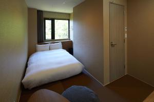 Habitación pequeña con cama y ventana en Hakone Yutowa, en Hakone