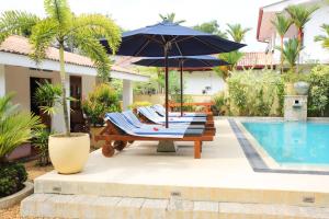 uma mesa com um guarda-sol ao lado de uma piscina em Sky and Sand Guesthouse em Beruwala
