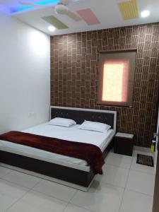 a bedroom with a bed and a brown tiled wall at No Problem Guest House in Moga