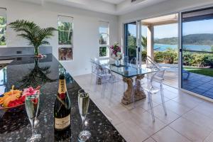 uma sala de jantar com uma mesa de vidro e garrafas de vinho em La Bella Waters 1 Wide Reaching Ocean Views And Buggy em Hamilton Island