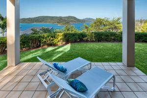 een patio met 2 stoelen en uitzicht op het water bij La Bella Waters 1 Wide Reaching Ocean Views And Buggy in Hamilton Island