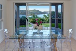 a glass table with chairs and a vase with flowers at La Bella Waters 1 Wide Reaching Ocean Views And Buggy in Hamilton Island