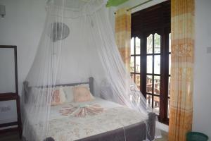 a bedroom with a bed with a mosquito net at Pasan Guest in Ella