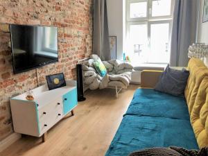 een woonkamer met een bank en een tv aan een bakstenen muur bij Apartament na Szczytnej - free PARKING in Toruń