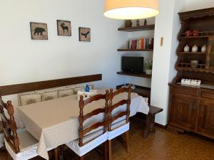 una sala da pranzo con tavolo, sedie e TV di Bilocale Sorgente a Ponte di Legno