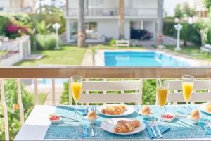 stół z talerzami jedzenia i szklanki soku pomarańczowego w obiekcie Pure Pool Sensation Apartment Sitges w mieście Sitges
