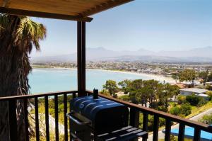 a suitcase sitting on a balcony overlooking a beach at Palm Tree Self-Catering Apartment in Gordonʼs Bay