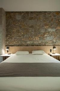 a bedroom with a bed with a stone wall at Art Suites Korai in Athens