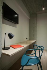 a blue chair sitting next to a desk with a television at Art Suites Korai in Athens