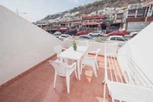 einen weißen Tisch und Stühle auf einem Balkon mit Stadtblick in der Unterkunft Montecarlo Apartamento39 in Puerto Rico de Gran Canaria
