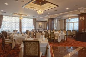 un restaurant avec des tables blanches, des chaises et des fenêtres dans l'établissement Drustar Hotel, à Silistra