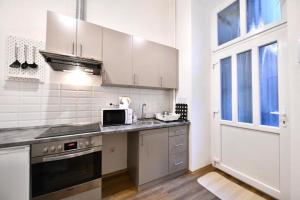 cocina con armarios blancos, fregadero y microondas en Cosy flat in Király str, Queen en Budapest
