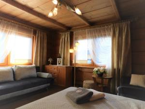 a bedroom with a bed and a couch and windows at Pokoje Goscinne Monika II in Zakopane