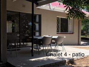 un patio con mesa y sillas frente a una casa en Impala Chalets, en Phalaborwa