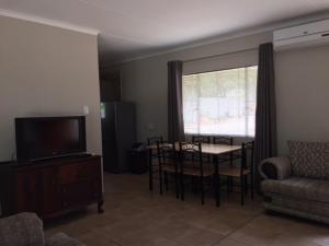 a living room with a tv and a table and chairs at Impala Chalets in Phalaborwa