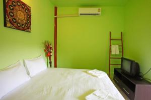 a green bedroom with a bed and a tv at PP Red Tuna Hut in Phi Phi Don