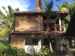 a building with a straw roof and palm trees at The Broken Board in General Luna