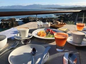 a table with plates of food and drinks on it at Cliff Lodge in Gansbaai