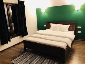 a bedroom with a large bed with a green wall at Popasul din Pietrar in Preluca Veche