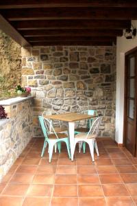 uma mesa e cadeiras em frente a uma parede de pedra em El Molín de La Vega Agroturismo em Ribadesella