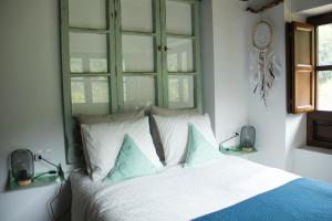 a bedroom with a bed with blue and white pillows at El Molín de La Vega Agroturismo in Ribadesella