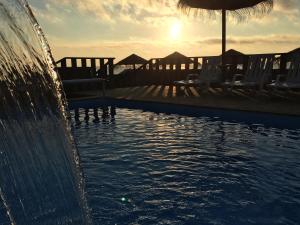 a swimming pool with chairs and an umbrella and the sunset at Promar - Eco Beach & Spa Hotel in Maceira