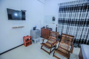 a room with two chairs and a tv and a table at Sunstar Nilaveli in Trincomalee