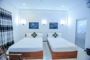 two beds in a room with white walls at Sunstar Nilaveli in Trincomalee