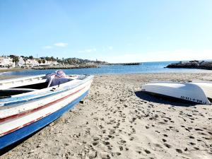 two boats sitting on a beach next to the water at El Nogal Home in Málaga
