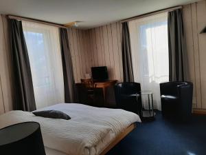 a hotel room with a bed and two chairs at Hotel Restaurant Le Giétroz in Le Châble