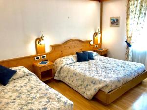 a hotel room with two beds and two tables at Cesa Bernard in Pozza di Fassa