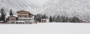 a large house with a snow covered mountain in the background at Hotel Landhaus Tirolerherz in Sankt Ulrich am Pillersee