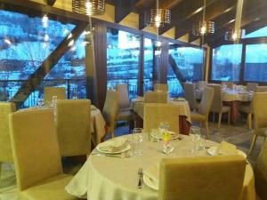 un restaurante con mesas y sillas blancas y ventanas en Hotel Ca de Graus, en Castanesa