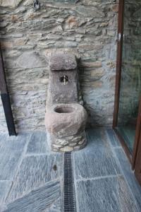 a stone toilet in the corner of a stone wall at Hotel Ca de Graus in Castanesa