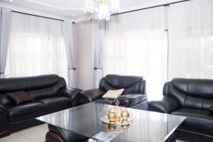 sala de estar con sillas de cuero negro y mesa de cristal en Villa Prince en Harare