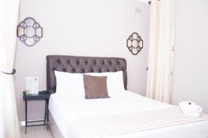 1 dormitorio con cama blanca y cabecero negro en Villa Prince en Harare