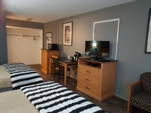 a hotel room with two beds and a desk with a television at Metro Inn in Victoria