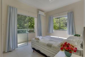 1 dormitorio con 1 cama y 2 ventanas en Lopes Residence 100 metros do mar Ingleses, en Florianópolis