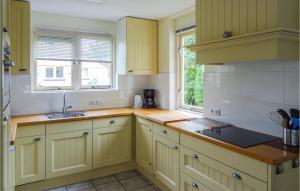 a kitchen with yellow cabinets and a sink and a window at Oesterbaai 6 in Wemeldinge