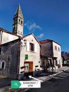 an old building with a clock tower on a street at Apartment Mediterraneo Blue Sky in Perast