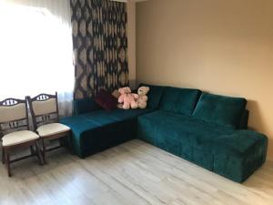 ein Teddybär auf einer grünen Couch im Wohnzimmer in der Unterkunft Садиба Червона калина Private estate Chervona Kalyna in Jaremtsche