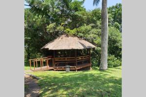 a gazebo with a straw roof in a park at 23 Manzini Chalets-Pumba's Den in St Lucia