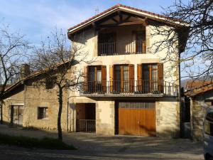 Casa de piedra antigua con balcón en una calle en Angoiko Etxea, en Bacáicoa