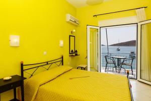 a yellow bedroom with a bed and a balcony at Xenon Christina in Vivari