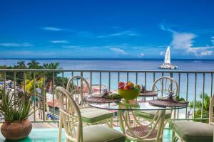 a table with a bowl of fruit on a balcony with the ocean at Montego Bay Club Apartments in Montego Bay
