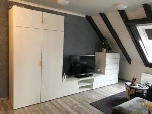 a living room with a tv and a white cabinet at Apartment Elegance in Höheischweiler